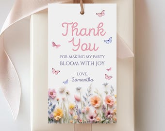 May include: A gift tag with the words "Thank You" in pink script, adorned with butterflies and a floral border. The tag reads "For making my party bloom with joy, Love, Samantha." The tag is tied to a cream-colored gift box with a pink ribbon.