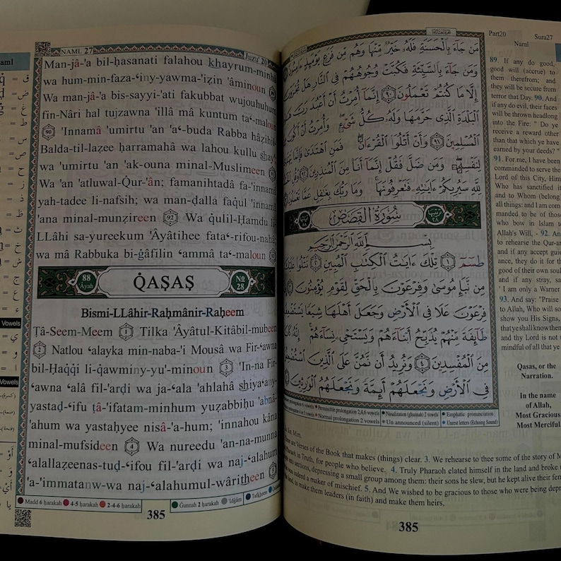 May include: Two pages from a Quran, an Islamic holy book, open to a section titled "Qasas". The pages are printed in Arabic script with black text on a white background. The text is surrounded by a black border. The page on the left has a green border and the page on the right has a blue border. The text on the left page is in Arabic script and the text on the right page is in Arabic script and English.