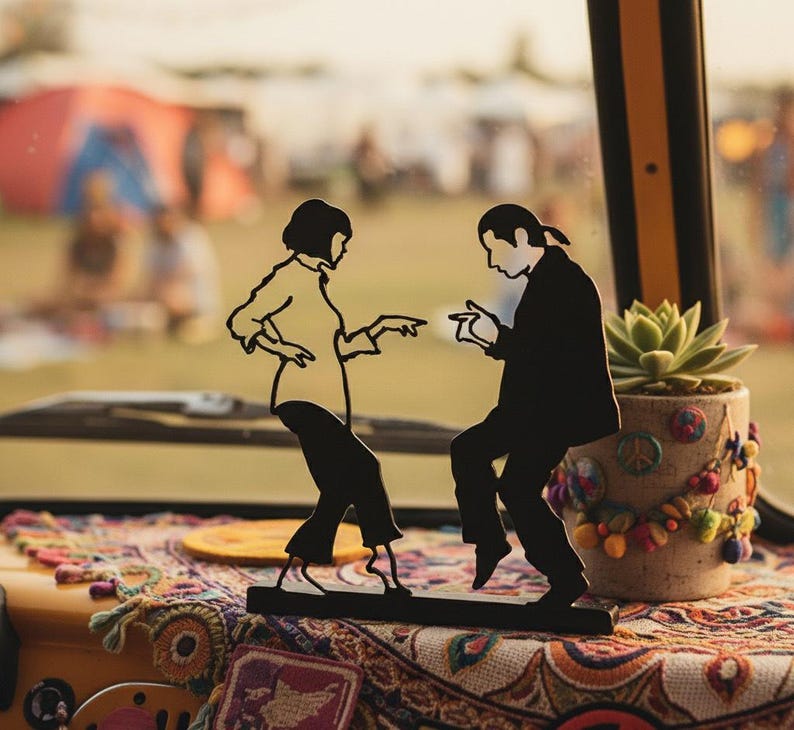 May include: A black metal silhouette sculpture depicting two figures in a dancing pose, mounted on a rectangular base. The design features a person with a bob haircut and a person with a ponytail, both dressed in shirts and trousers, mid-dance.