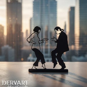 May include: A black metal silhouette sculpture depicting two figures dancing, with one figure in a shirt and pants and the other in a suit, both standing on a rectangular base. The text DERVART dekoratif &uuml;r&uuml;nler is printed in white at the bottom left.