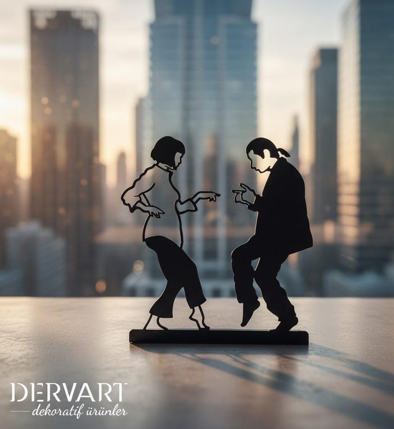 May include: A black metal silhouette sculpture depicting two figures dancing, with one figure in a shirt and pants and the other in a suit, both standing on a rectangular base. The text DERVART dekoratif &uuml;r&uuml;nler is printed in white at the bottom left.