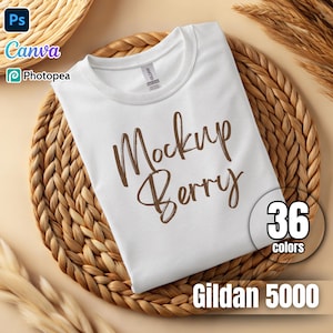 Puede incluir: Maqueta de camiseta blanca con el texto "Mockup Berry" en letras marrones. La camiseta está sobre una superficie de mimbre tejido. También se puede ver el texto "36 colores" y "Gildan 5000".