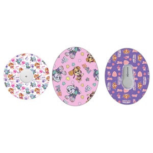 Puede incluir: Tres pegatinas redondas y coloridas con personajes del programa de dibujos animados Paw Patrol. Las pegatinas son de color rosa, morado y blanco con huellas de patas y las palabras "Trabaja duro, juega más duro".