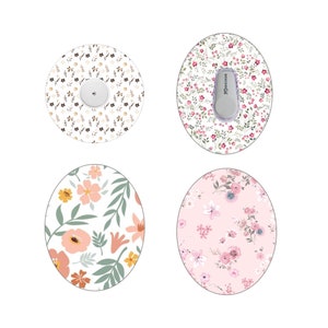 Puede incluir: Cuatro parches adhesivos con motivos florales para dispositivos médicos. Los diseños incluyen un parche redondo con un dispositivo blanco y un estampado floral marrón, y tres parches ovalados con diseños florales rosas, melocotón y blancos. Los parches son para dispositivos médicos.