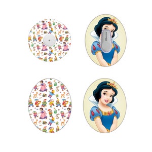 May include: Two oval-shaped stickers featuring Snow White from Disney's Snow White and the Seven Dwarfs. One sticker features Snow White with a light blue dress and a crown. The other sticker features Snow White with a light blue dress and a crown, and a pattern of Snow White and the Seven Dwarfs. The text "FreeStyle Libre" is visible on the sticker.