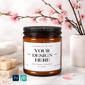 May include: A brown soy wax candle in a glass jar with a black lid. The label reads "YOUR DESIGN HERE" and "CANDLE & CO". The background includes pink flowers, a white vase, and bars of soap.