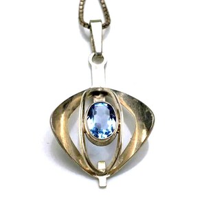 Peut inclure: Un collier avec un pendentif en argent orné d'une pierre précieuse bleue dans un design géométrique.