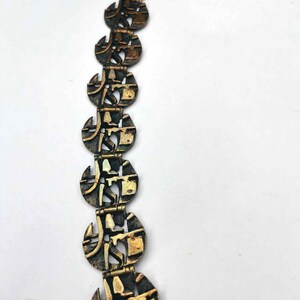May include: A gold-toned bracelet with a chain link closure. The bracelet is made of multiple linked circular pieces with an intricate geometric design.