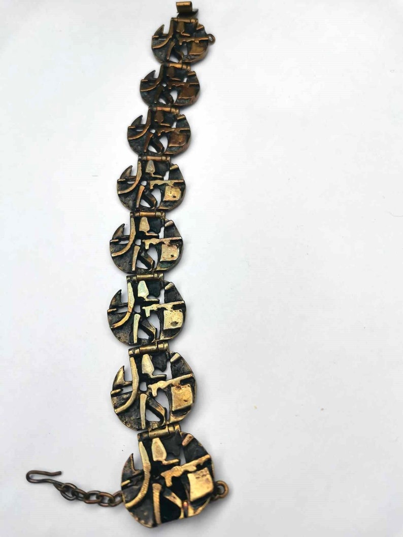 May include: A gold-toned bracelet with a chain link closure. The bracelet is made of multiple linked circular pieces with an intricate geometric design.