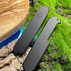 May include: Two black textured custom knife scales with a medical symbol and a notched design. The scales are displayed on a natural wood and moss background. The logo "FORGE BONE CUSTOM ESTD 2024" is visible in the background.