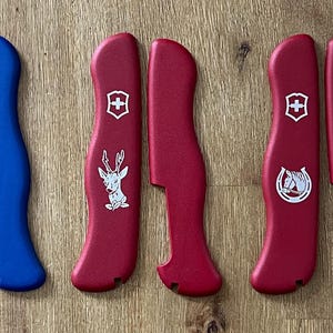 Peut inclure: Huit couteaux de poche de couleurs différentes avec différents motifs sur les manches. Les motifs comprennent une boussole, un cerf, un fer à cheval et les mots "Rescue Tool".