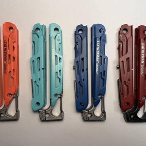 Könnte beinhalten: Vier Multitools in Orange, Türkis, Blau und Rot. Jedes Werkzeug ist mit "LEATHERMAN SIGNAL" beschriftet und verfügt über einen Karabinerhaken. Die Werkzeuge haben ein robustes, zweckmäßiges Design.