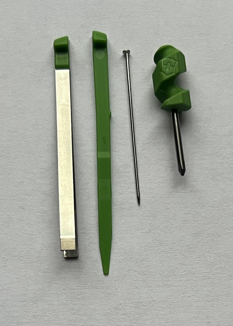 May include: Three tools for crafting: a green plastic needle tool, a green plastic tool with a pointed end, and a silver metal tool with a white stripe.
