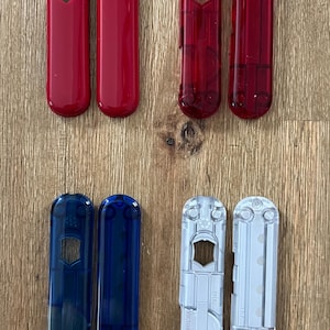Puede incluir: Seis escamas de plástico de diferentes colores para una navaja multiusos. Las escamas son rojas, rojo transparente, azules, azul transparente, plateadas y plateadas transparentes.