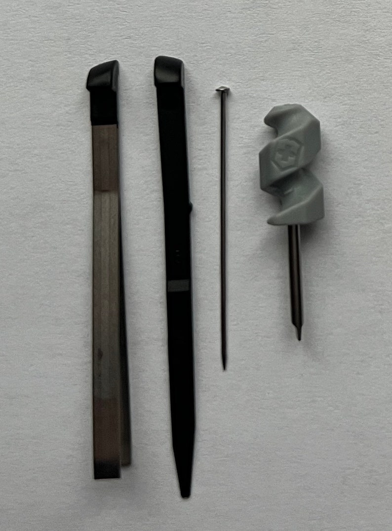 May include: Three tools for crafting: a black metal tool with a pointed tip, a silver metal tool with a flat tip, and a gray plastic tool with a spiral design.