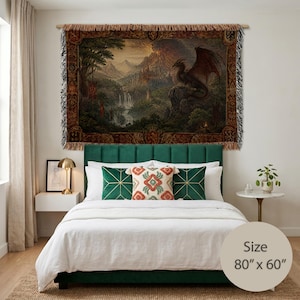 Könnte beinhalten: Ein gewebter Wandteppich mit den Maßen 203 cm x 152 cm, der eine detaillierte Landschaftsdarstellung eines geflügelten Drachen auf einer Felsklippe über einem Vulkanberg, Wasserfällen und einem Wald zeigt, umrahmt von einer dekorativen Bordüre.