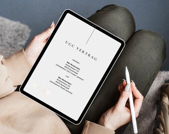Puede incluir: Una persona sostiene una tableta que muestra el texto "UGC VERTRAG" en fuente negra. La tableta es blanca con un borde negro. Un lápiz óptico blanco se sostiene en la mano derecha. La persona lleva un suéter beige y pantalones verde oliva.