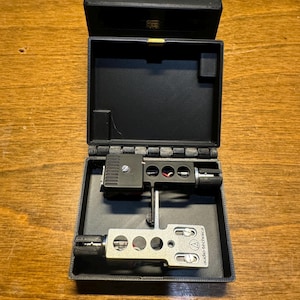 May include: A black box with the words "AGAVE AUDIO" printed on the top. The box is open and contains a silver and black audio-technica cartridge.