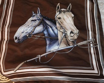 Può includere: Un foulard di seta marrone con bordo bianco presenta un'illustrazione dettagliata di due teste di cavallo con briglie e una frusta.