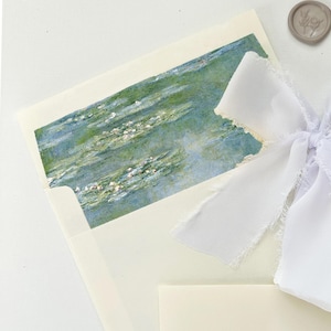 May include: An off-white envelope with a watercolor painting of a water garden. A white ribbon is tied to the envelope. A small, round, gray wax seal with a floral design is also present.