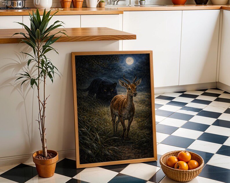 May include: A framed art print depicts a deer in a moonlit forest, with a black panther in the background. The artwork is in a wooden frame and is leaning against a white wall. A potted plant and a basket of oranges are also in the scene.
