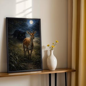 May include: Framed art print featuring a deer in a forest setting under a full moon, with a black panther in the background. The artwork is displayed on a wooden shelf with a white vase and yellow flowers.