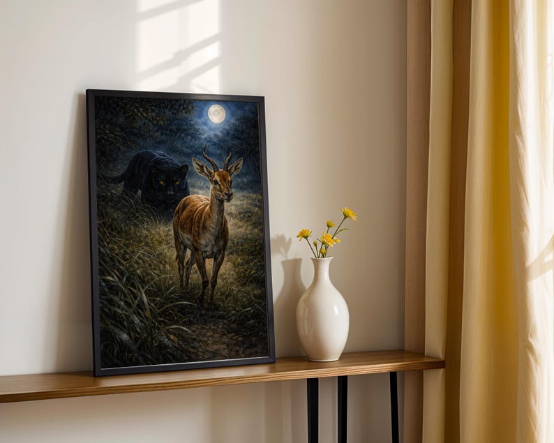 May include: Framed art print featuring a deer in a forest setting under a full moon, with a black panther in the background. The artwork is displayed on a wooden shelf with a white vase and yellow flowers.