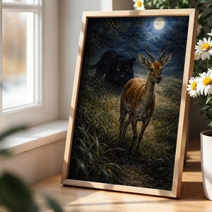 May include: A framed art print depicts a deer in a grassy area, with a black panther in the background under a full moon. The artwork is in a wooden frame, and the scene is set in a forest. The print is displayed near a window.