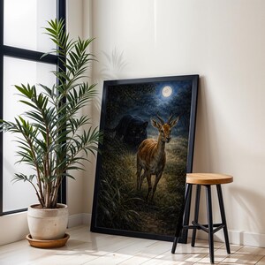 May include: A framed art print depicts a deer in a moonlit forest, with a black panther in the background. The artwork is in a black frame, leaning against a white wall. A potted plant and a wooden stool are also in the scene.