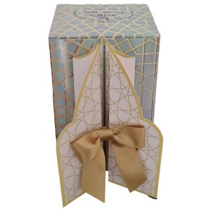 May include: A decorative gift box with a geometric pattern in shades of blue, gold, and white. The box has a gold bow and a flap that opens to reveal a pink interior with a gold geometric pattern.