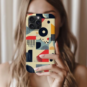 May include: A smartphone case with a colorful geometric design. The case features a pattern of red, blue, yellow, and black shapes on a cream background. The phone case has a camera module with three lenses.