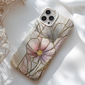 May include: A phone case featuring a floral design with a stained glass effect. The case has a white and beige background with a large pink and purple flower. Gold-colored lines outline the flower petals.