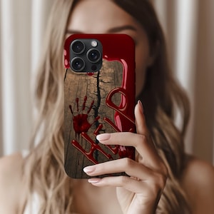 May include: A red phone case with a wood grain effect, displaying red handprints and dripping blood. The case has a glossy finish and a dark red border. The design creates a horror theme.