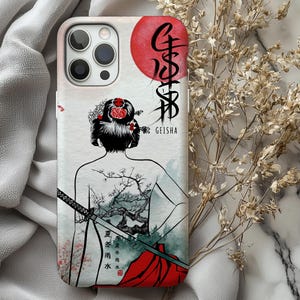 Op de afbeelding: Een telefoonhoesje met een geisha-ontwerp. De hoes toont een geisha van achteren, met een zwaard, een rode zon en Japanse tekst. Het woord "GEISHA" is in het wit gedrukt. De hoes heeft een witte achtergrond.