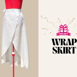 May include: A white wrap skirt made of a silky fabric, displayed on a red dress form. The skirt has a wrap design with a tie closure. The image also includes the text "WRAP SKIRT" and a "FREE GIFT" graphic.