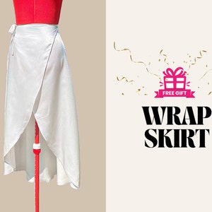May include: A white wrap skirt made of a silky fabric. The skirt is displayed on a red mannequin and tied at the waist. The text "WRAP SKIRT" is displayed in bold, black letters.