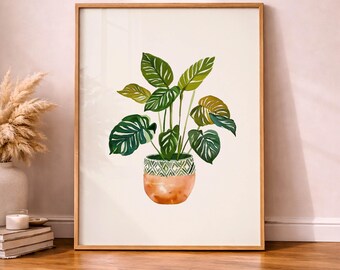 May include: Watercolor painting of a potted plant with large green leaves and a patterned pot. The pot is a mix of orange and white. The artwork is framed in a light brown wooden frame.