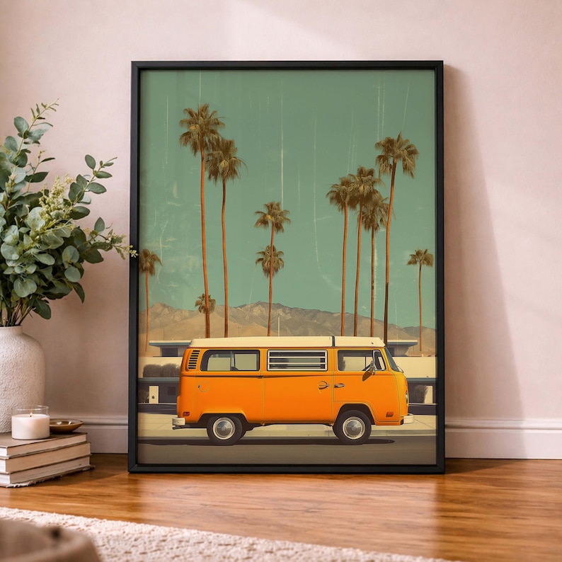 May include: Framed art print featuring an orange vintage van driving on a road with palm trees and mountains in the background. The sky is a teal color. The print is in a black frame.