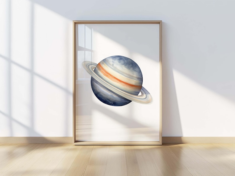 May include: A framed wall art print featuring a watercolor illustration of the planet Saturn. The planet is depicted with shades of deep blue, grey, and orange, surrounded by prominent rings in light beige and white tones, set against a white background.
