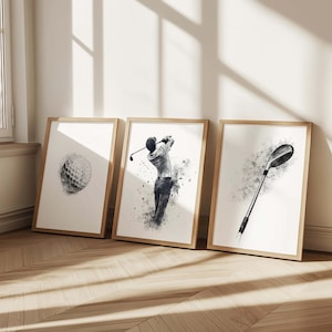 May include: Three framed golf-themed art prints. The prints feature a golf ball, a golfer mid-swing, and a golf club. The artwork is in black and white with a watercolour effect, set in wooden frames.