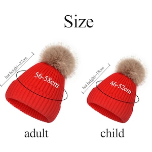 May include: Two red knit beanies with beige faux fur pom-poms. The adult beanie has a height of 22 cm and a circumference of 56-58 cm. The child beanie has a height of 18 cm and a circumference of 46-52 cm. The text Size, adult, and child is visible.