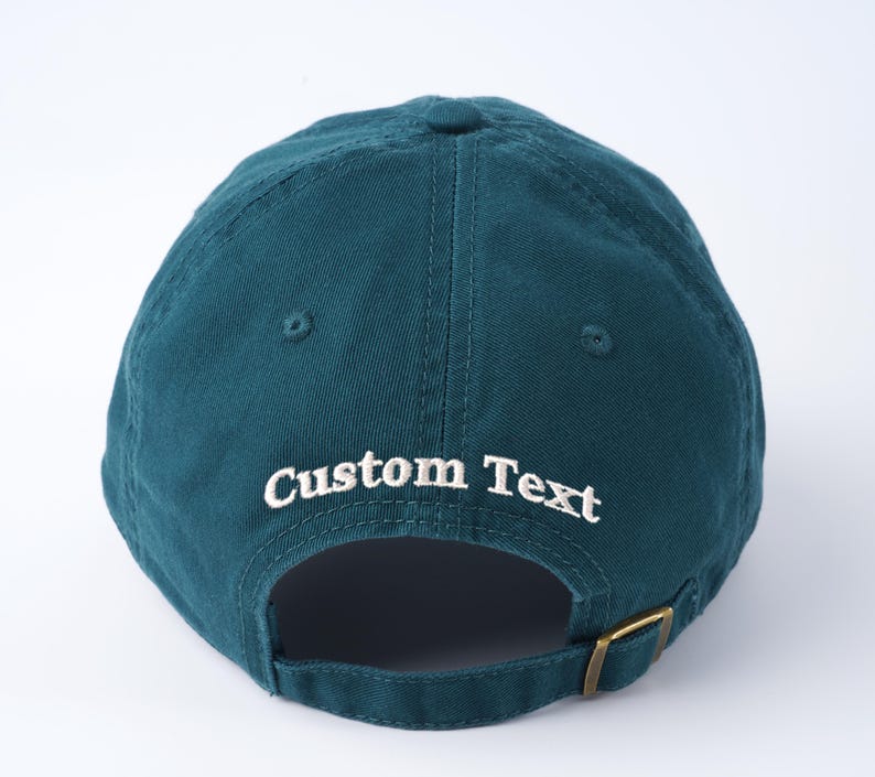 May include: A teal blue baseball cap with an adjustable strap and white embroidered text that says "Custom Text".