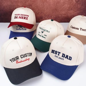 May include: A collection of baseball caps in various colors, including white, navy, red, green, and tan. Each cap features custom embroidery with phrases like "YOUR DESIGN IN HERE," "BEST DAD," and "YOUR CUSTOM Embroidery."