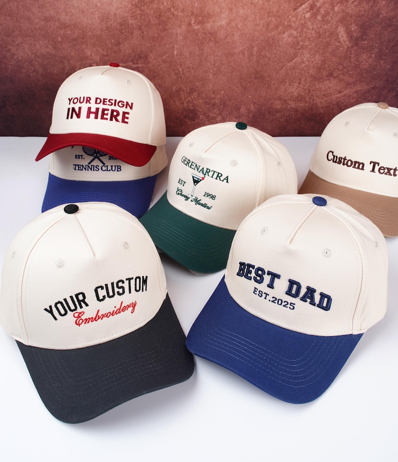 May include: A collection of baseball caps in various colors, including white, navy, red, green, and tan. Each cap features custom embroidery with phrases like "YOUR DESIGN IN HERE," "BEST DAD," and "YOUR CUSTOM Embroidery."