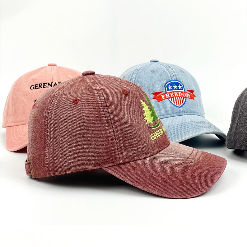 May include: Several baseball caps in shades of pink, burgundy, and light blue. The burgundy cap has a green tree design and the word "GREEN". The light blue cap features a "FREEDOM" emblem.