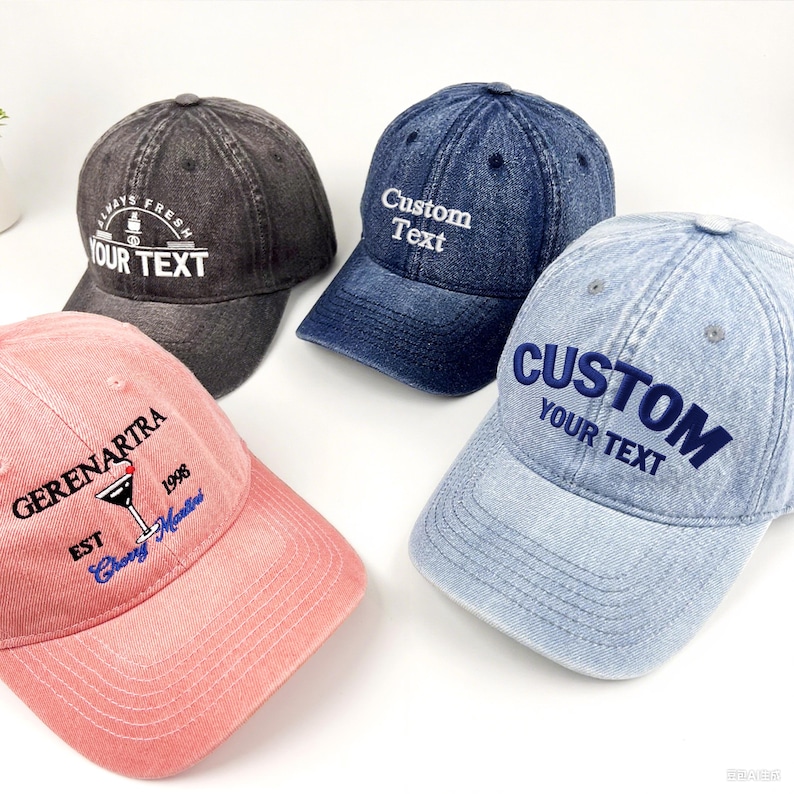 May include: Four baseball caps in different colours: black, navy blue, light blue, and pink. Each cap has embroidered text, including "Custom Text," "Always Fresh," and "Gerenartra." The caps have a classic, casual style.