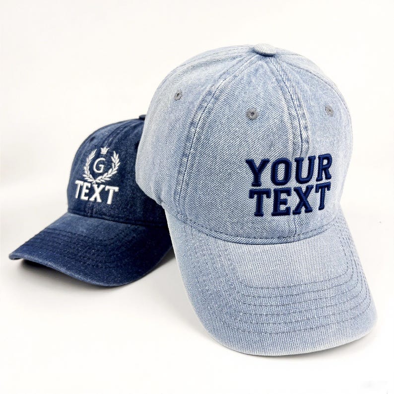 May include: Two denim baseball caps. One is a light blue wash with the text "YOUR TEXT" embroidered in navy blue. The other is a darker blue with the text "TEXT" and a "G" emblem embroidered in white.