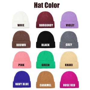 May include: Twelve different colored knit beanies with white text on each beanie. The colors are white, burgundy, violet, brown, black, grey, pink, green, khaki, navy blue, caramel, and rose red. The text on each beanie reads: WHIE, BURGUNDY, VIOLET, BROWN, BLACK, GREY, PINK, GREEN, KHAKI, NAVY BLUE, CARAMEL, and ROSE RED.