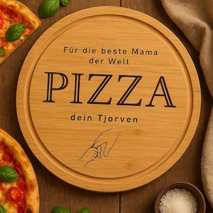 Könnte beinhalten: Rundes Pizza-Servierbrett aus Holz mit dem Wort "PIZZA" in großen, fetten Buchstaben. Das Brett hat den Text "Für die beste Mama der Welt" und "dein Tjorven" mit einer Zeichnung von zwei Händen. Pizzastücke und Basilikumblätter liegen auf der Holzoberfläche.