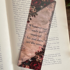 May include: A rectangular bookmark with a floral design featuring red and cream roses. The bookmark has a vintage aesthetic with script-style text that reads "Whatever our souls are made of, his and mine are the same."